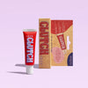 Red 'Clutch' glue tube and packaging on a light purple background
